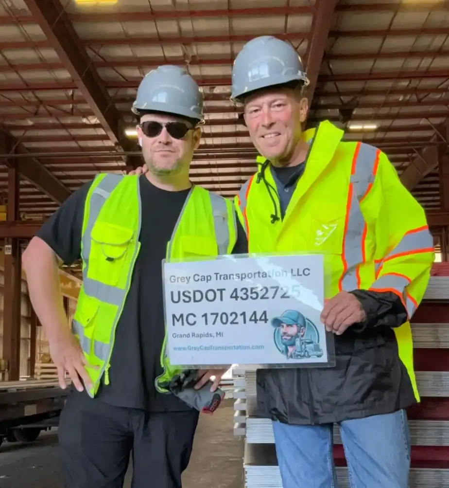 Two Grey Cap team members in safety gear holding company sign—showcasing compliance, professionalism, and local expertise.