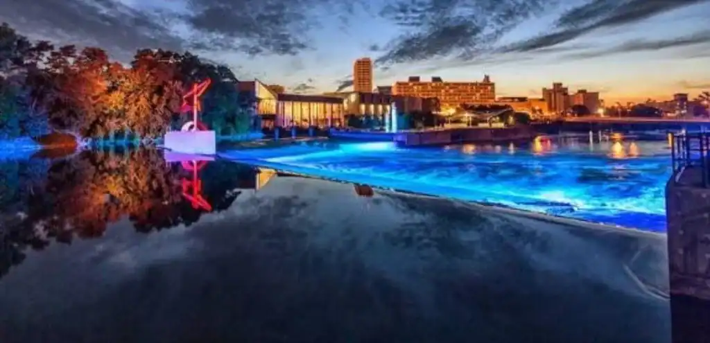 Illuminated riverwalk with sculpture and city skyline at dusk—Grey Cap service location highlight in South Bend, Indiana.